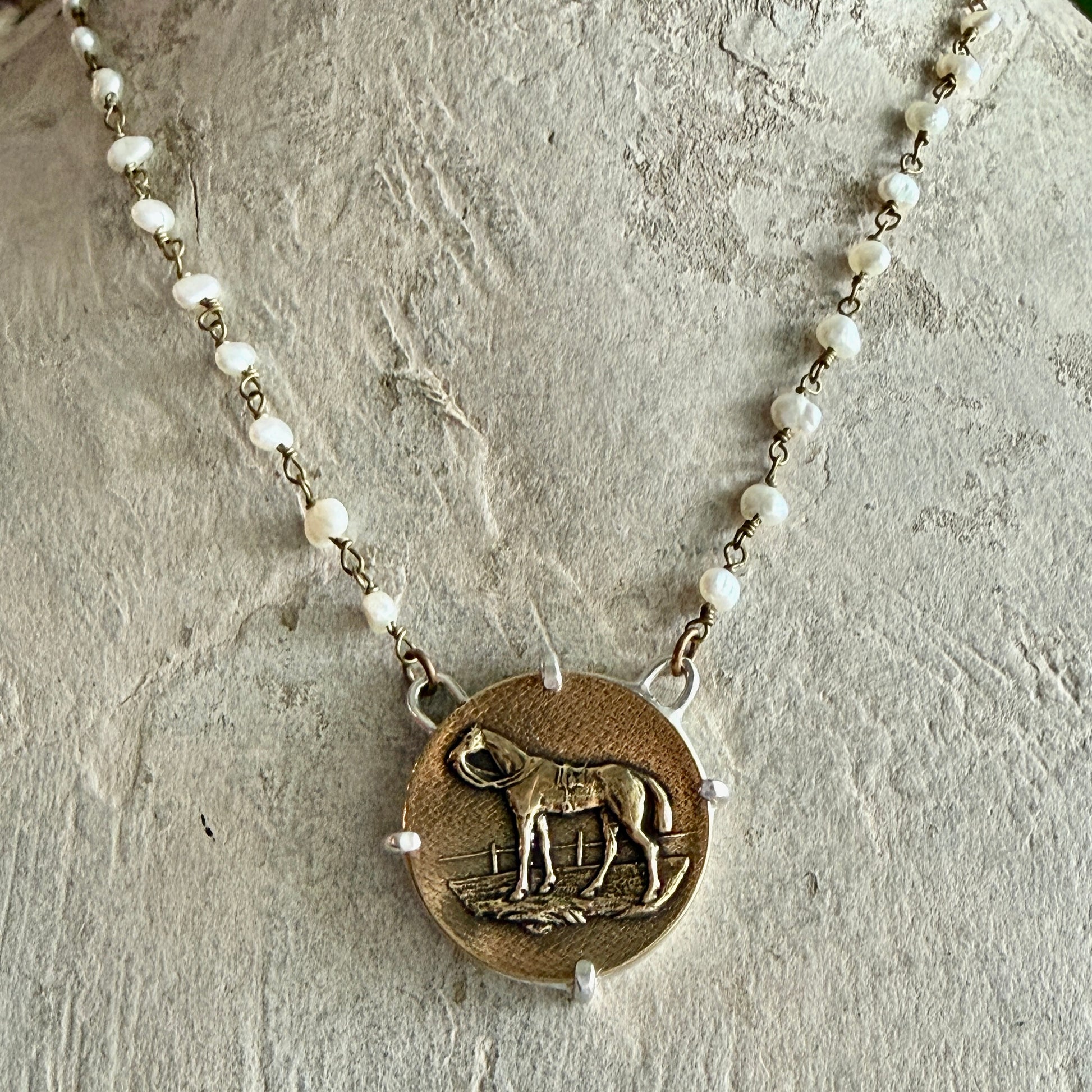 Necklace with a horse pendant on a textured surface